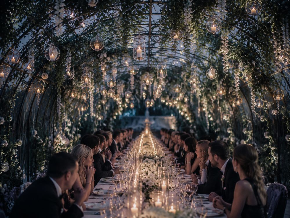 Wedding reception table decorated with a suspended botanical bridge of flowers and greenery