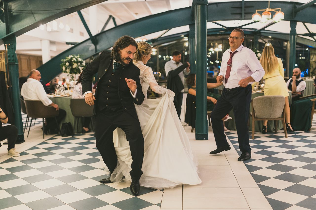 Newlyweds inviting family and friends onto the dance floor during a first dance transition at a wedding reception.