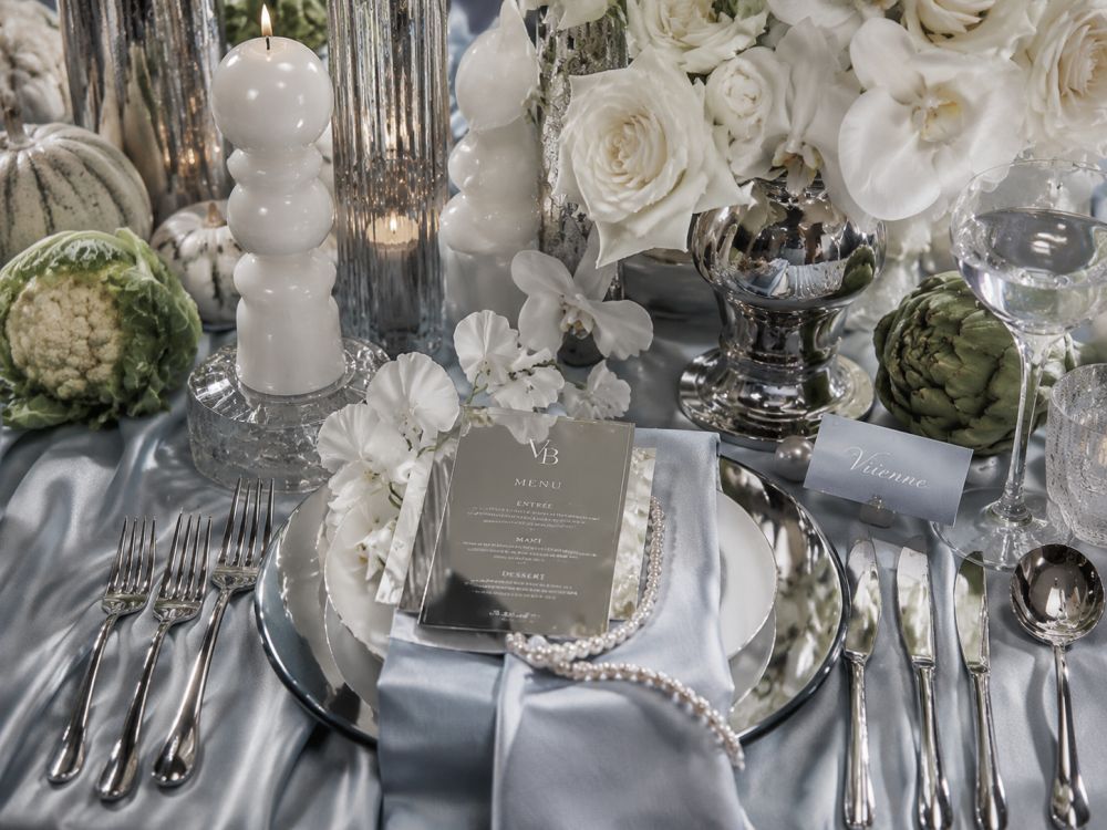 Luxury Neo Deco wedding table setting with chrome accents, sculptural flowers, pearls, mirrored stationery, and contemporary styling details.
