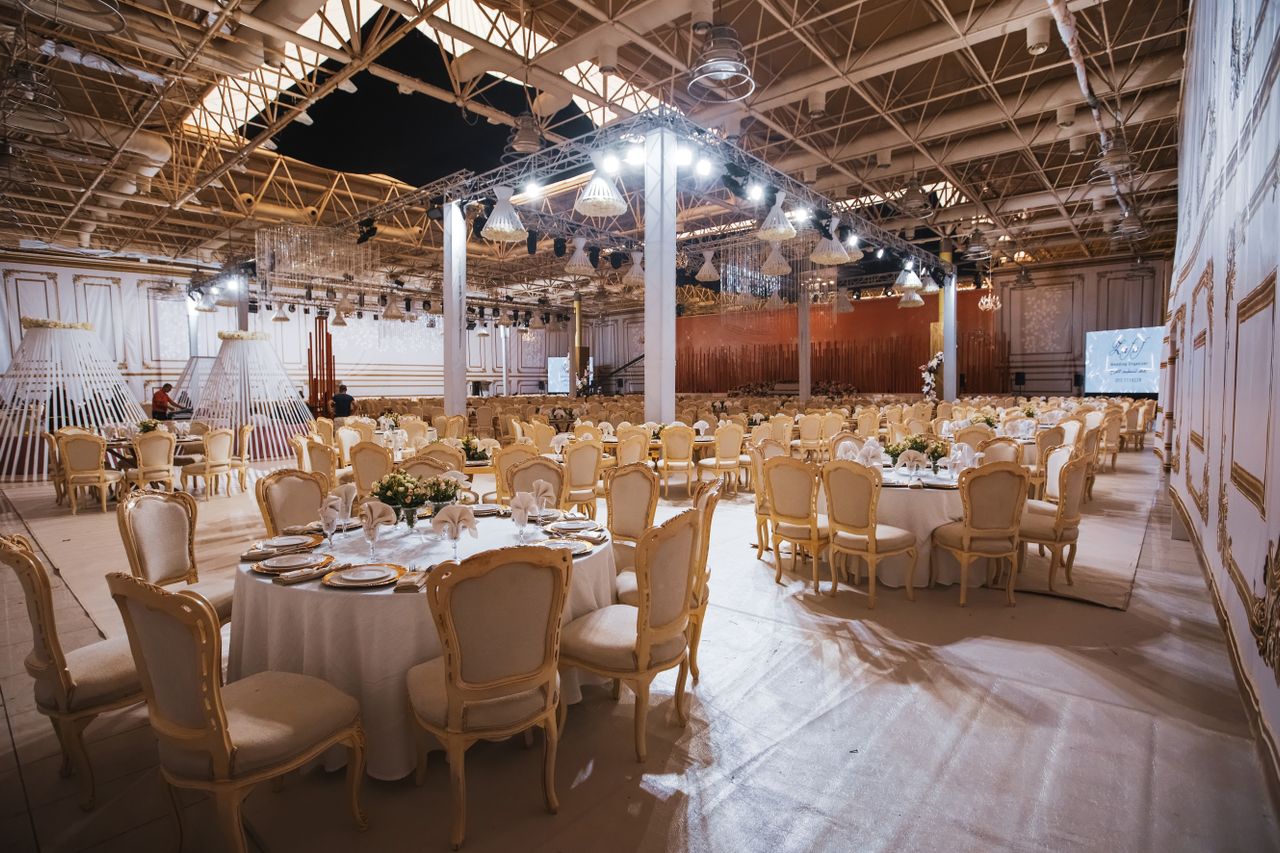 Engaged couple assessing reception room layout from the guest seating area during a venue tour.