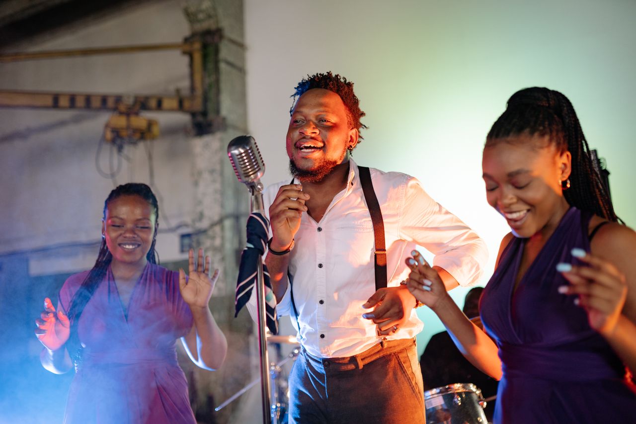 Wedding guests singing together with an acoustic musician during an emotional late-night reception moment.