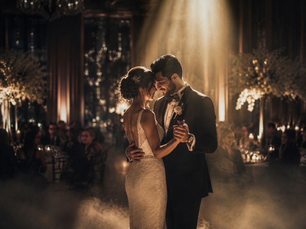 Newlyweds dancing under romantic spotlight lighting during an atmospheric wedding reception