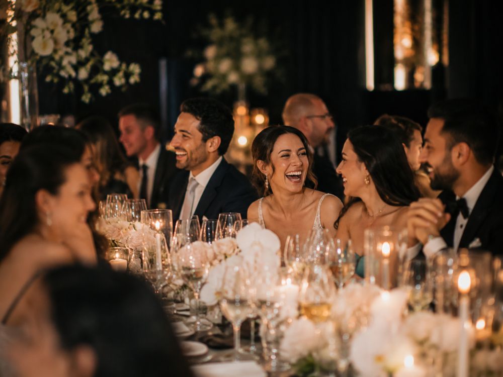 Wedding guests enjoying conversation and connection around a beautifully styled serpentine reception table.