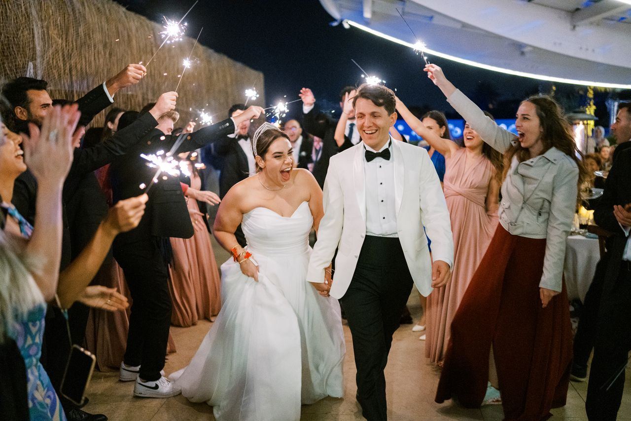 Wedding couple entering reception surrounded by indoor cold sparklers and cheering guests