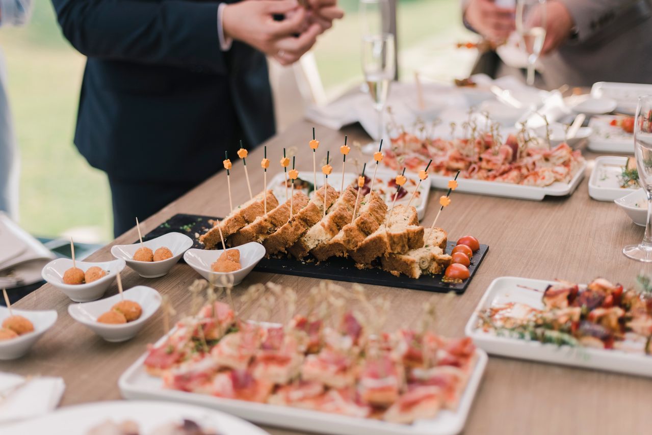 Gourmet wedding canapé station with chefs preparing small bites while guests gather and enjoy cocktail hour catering.