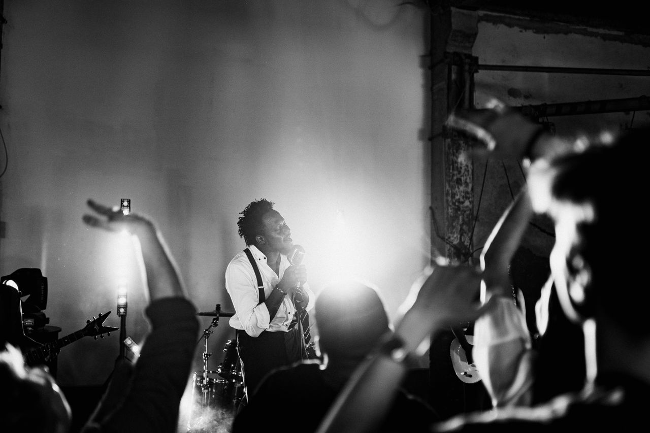 Vocalist performing live on a wedding stage while guests react with excitement during a high-energy wedding reception.