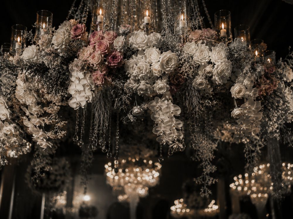 Close-up view of an elegant floral chandelier with roses and greenery above a wedding dance floor