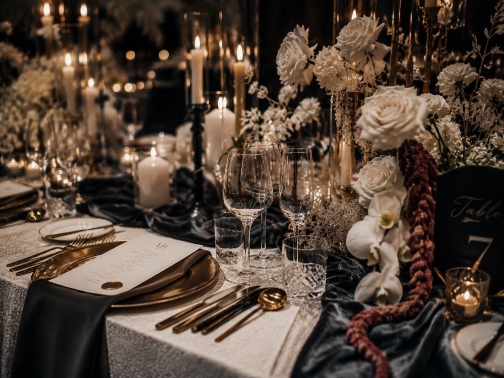 Close-up view of elegant winter wedding décor with candles, velvet textures, flowers, and luxury table styling.