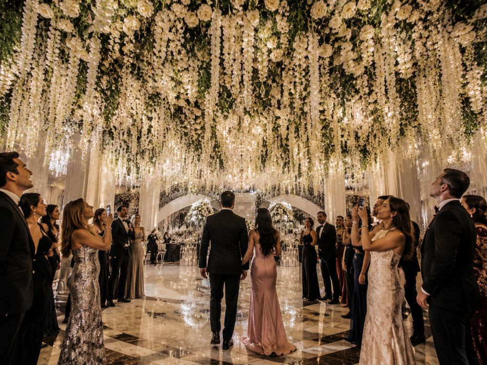 Guests admiring a dramatic hanging flower installation inside a Melbourne ballroom wedding venue