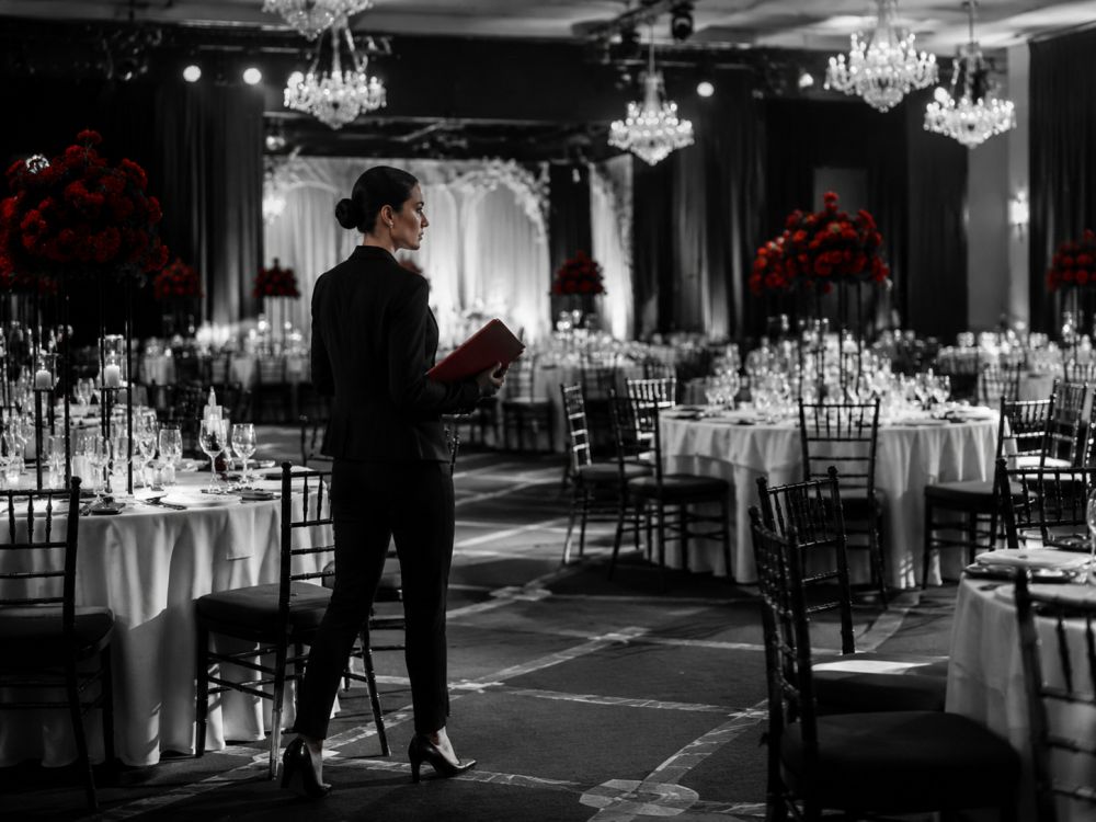 Event coordinator inspecting a reception venue and managing details before a wedding celebration begins.