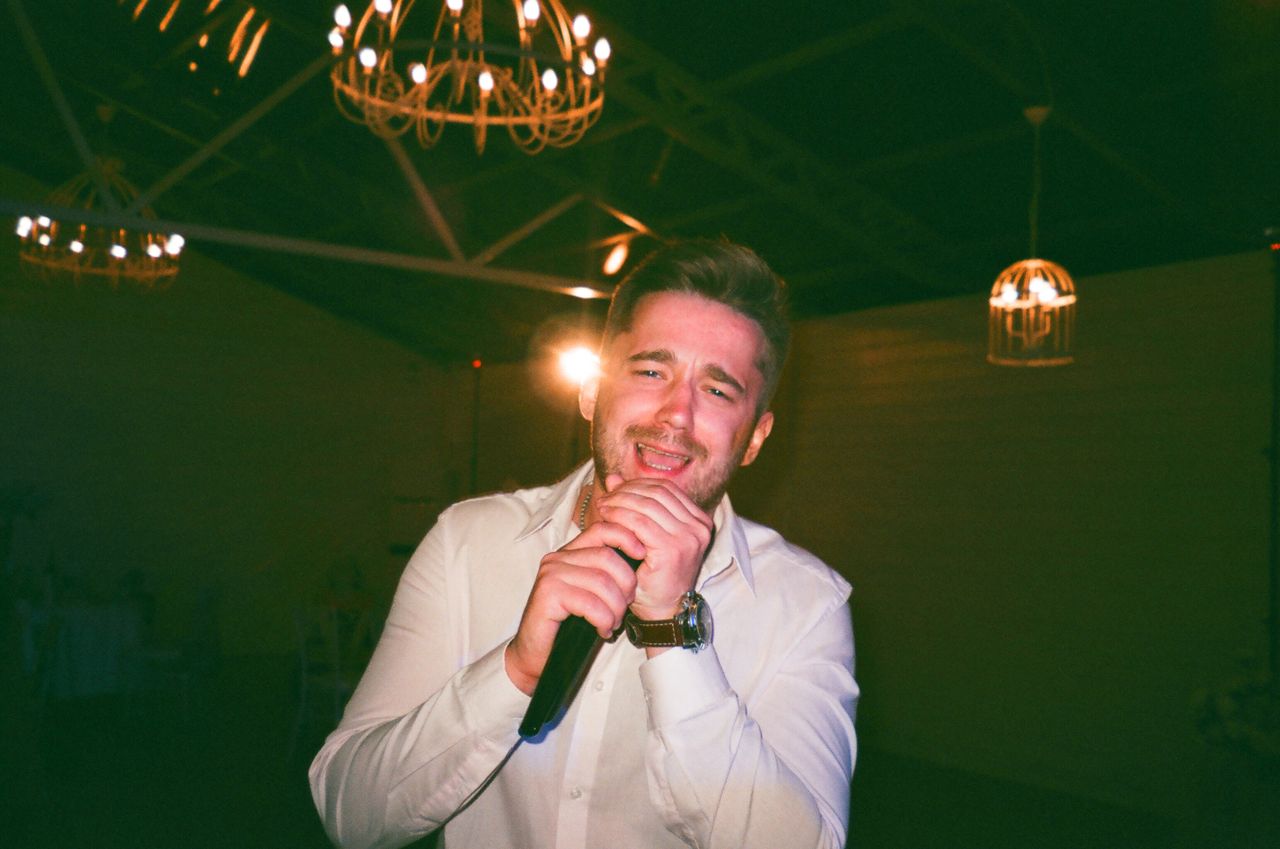 Surprise singing waiter performance creating laughter and excitement among guests during a wedding dinner reception.