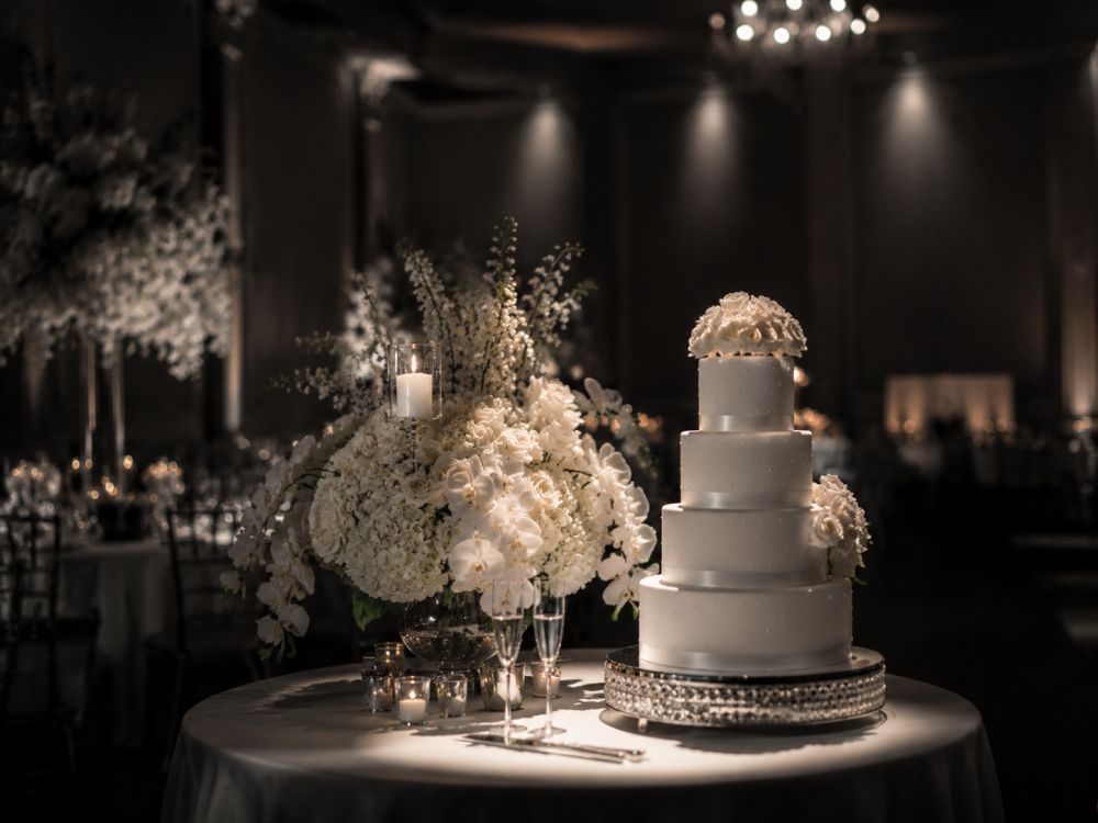 Wedding cake and floral centrepiece highlighted with professional pin spot lighting at a reception venue