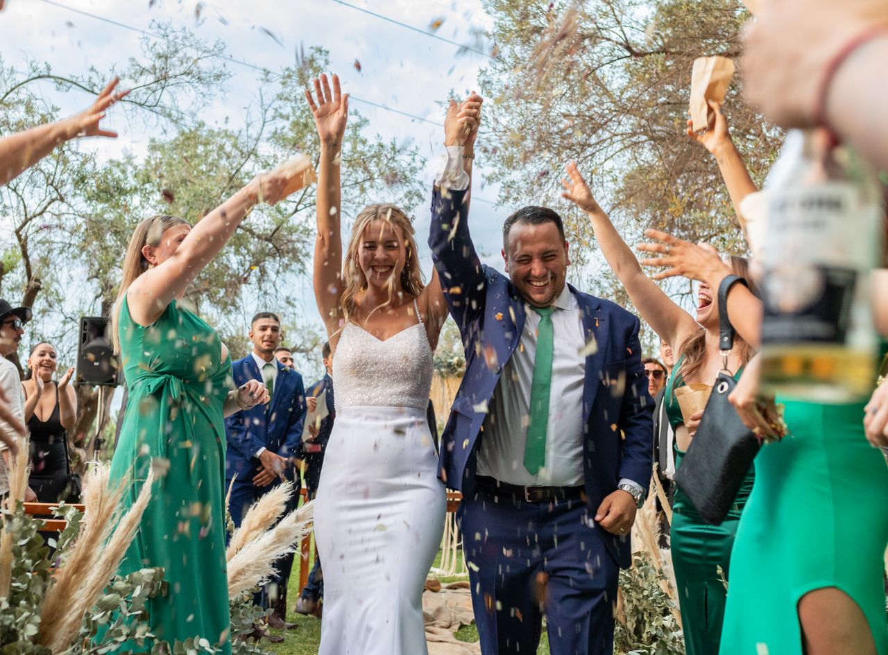 Newlyweds celebrating while walking through a tunnel of family and friends with confetti cannon at reception