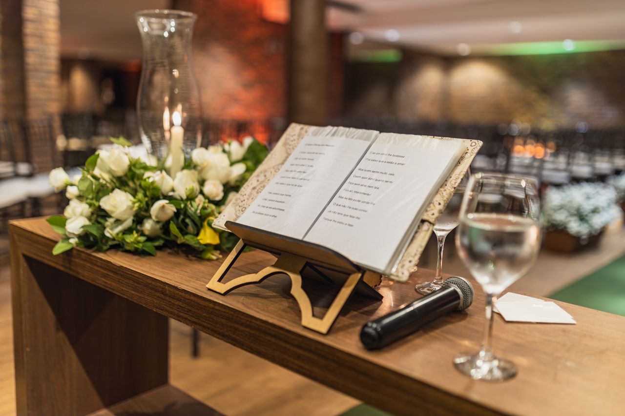 Close-up of a wedding reception run sheet with notes, microphone, place cards and wedding ring showing event organisation